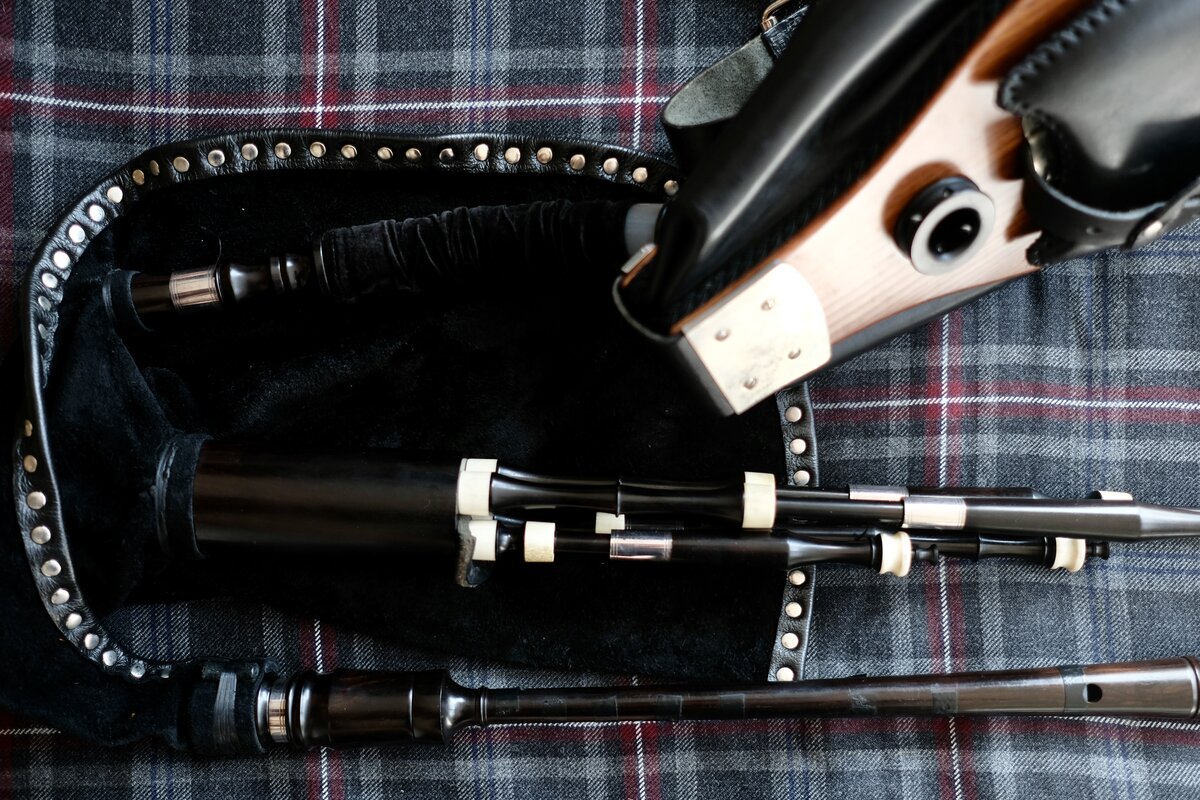 Border pipes with leather bag and chanter resting on a tartan rug