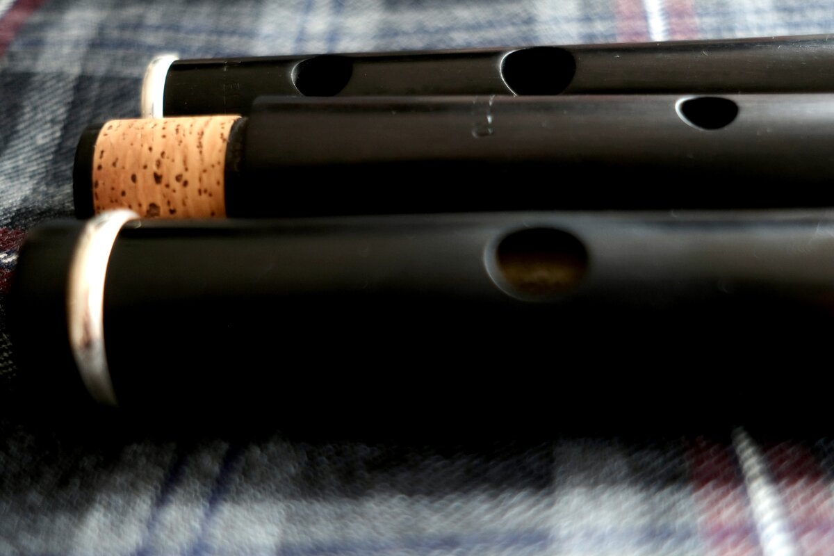 Close-up of an Olwell Irish flute and pennywhistles in African blackwood, with cork tenon joint visible
