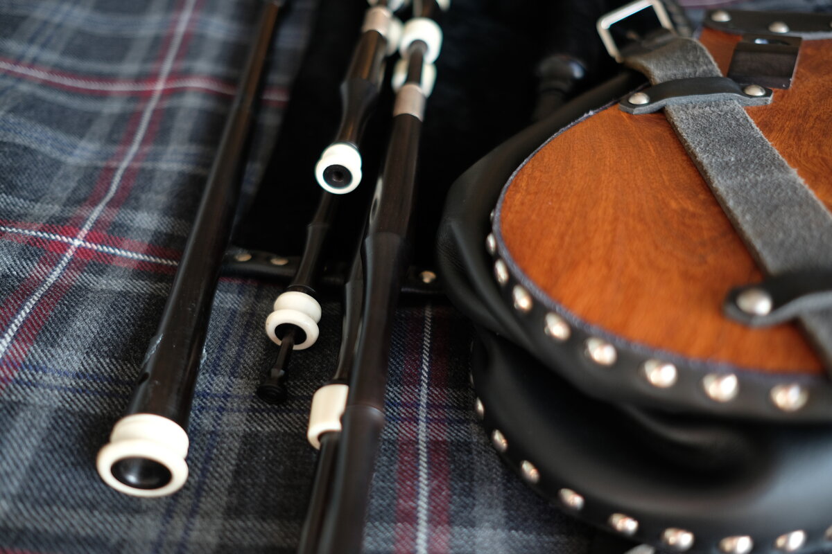 Scottish smallpipes laid out alongside a leather sporran on a tartan rug
